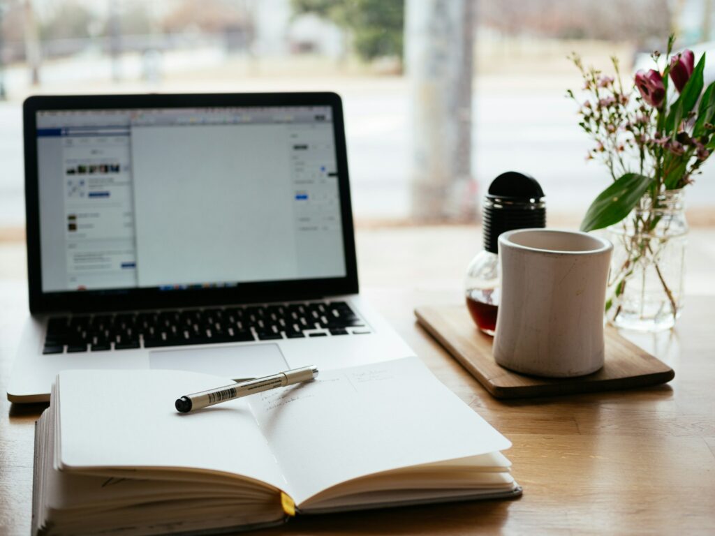 laptop, notebook and a coffee mug on a desk